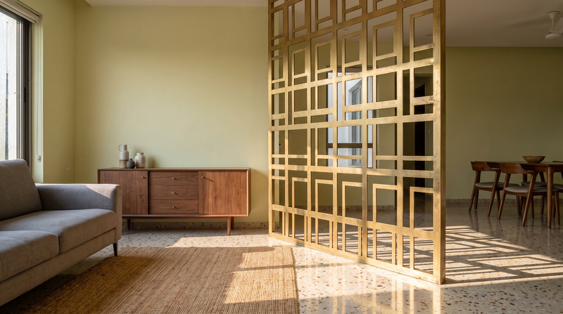 Laser-cut brass metal screen used as a room divider in a contemporary Indian home
