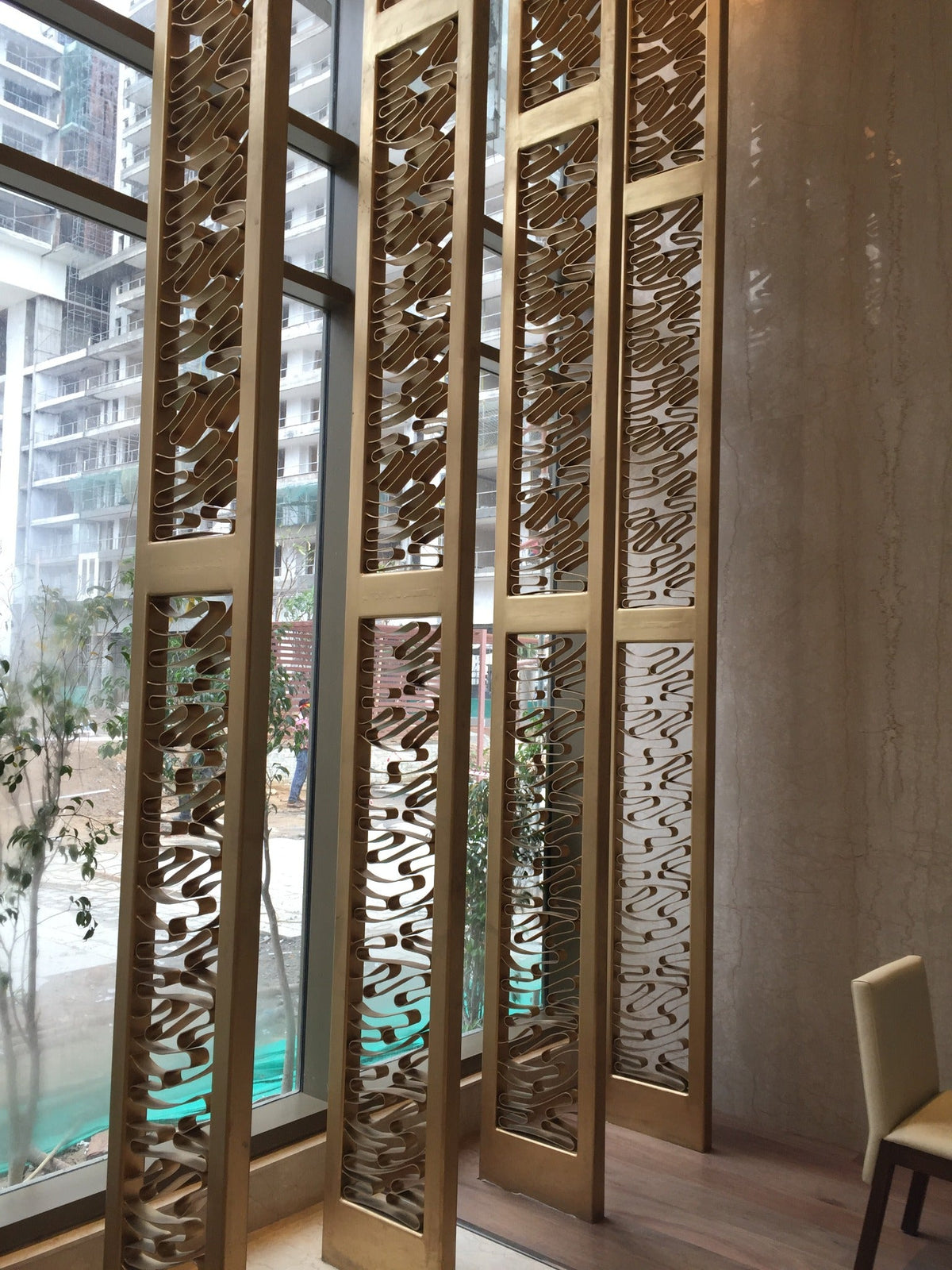 Handcrafted 25 ft mild steel decorative screen beside double height lobby glazing at M3M Golf Estate