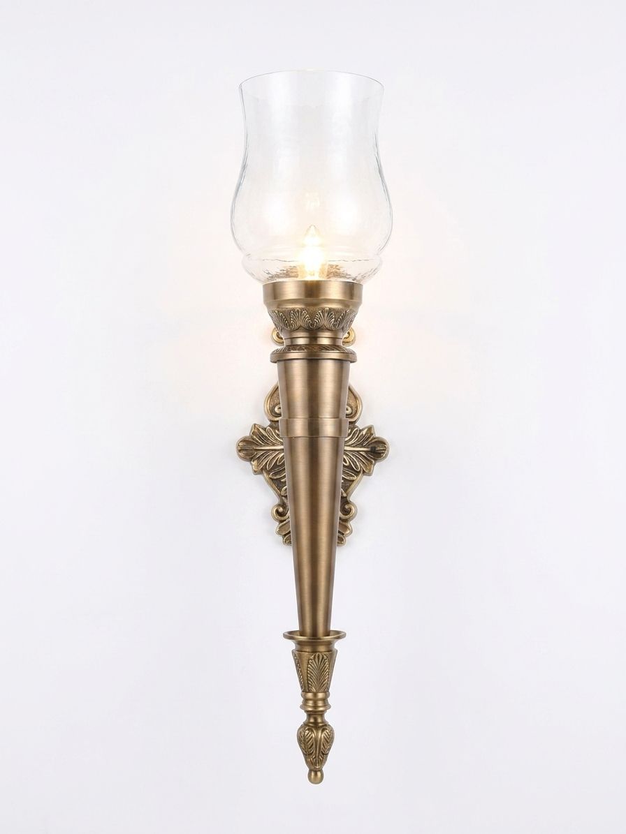 Ornate Torch Hurricane Sconce, a brass and glass wall light, studio photograph on a white background
