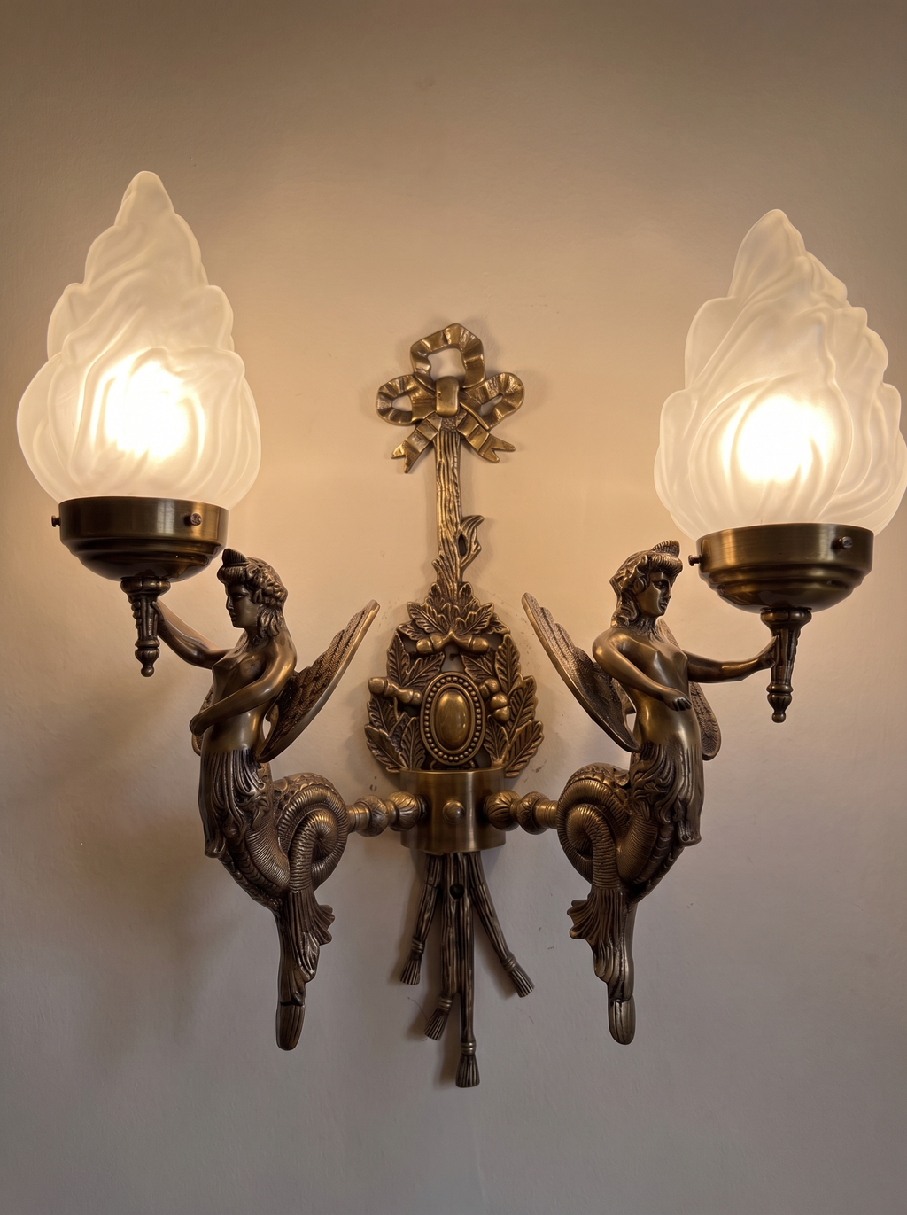 Apsara Double Wall Light switched on, the frosted flame shades glowing warm white