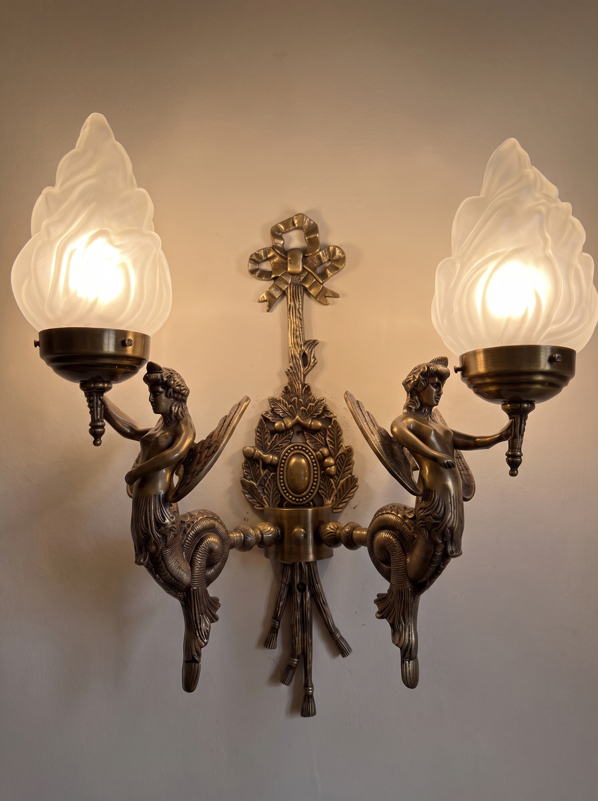 Apsara Double Wall Light switched on, the frosted flame shades glowing warm white
