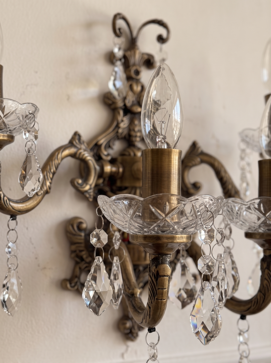 Close-up of the scrolled brass crest, a scalloped cut-glass bowl and crystal drops