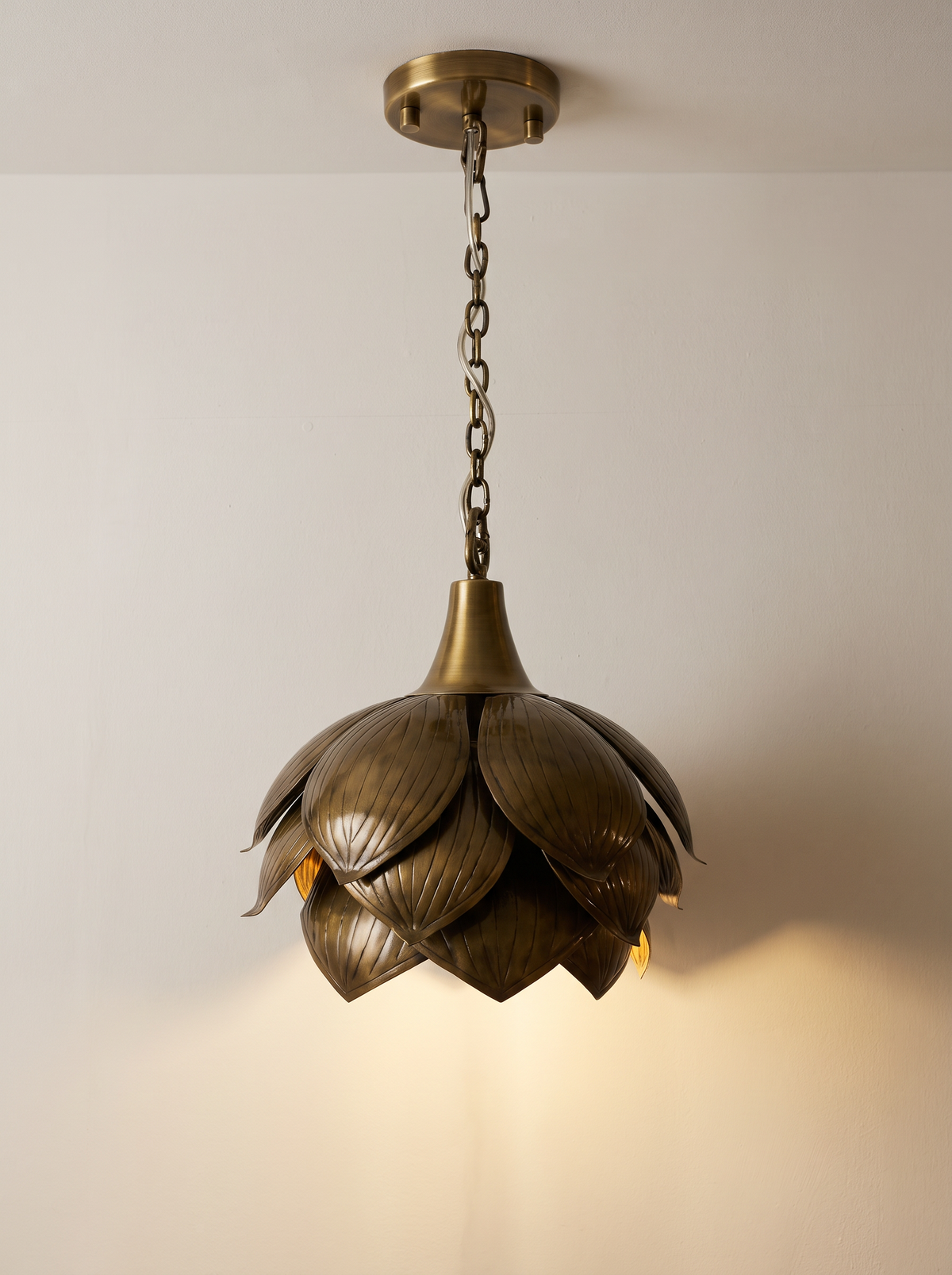 Brass Petals Pendant, Small, switched on, with warm light falling from the base