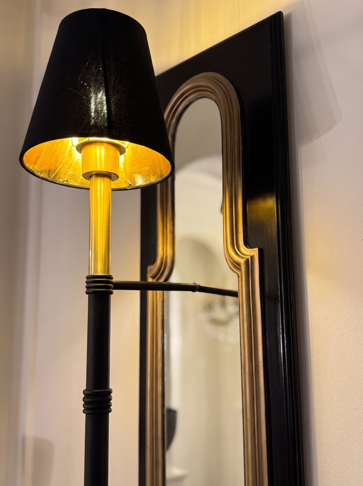 Close-up of the gold-lined black shade, polished brass top and the arched gold mirror frame