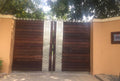 Wood main gate with paired floral metal jali panels