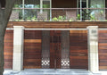 Wood main gate with paired geometric metal jali panels