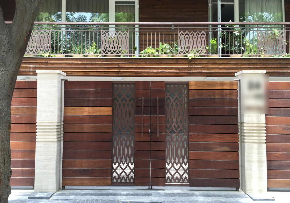 Wood main gate with paired geometric metal jali panels
