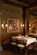 Pair of Directoire brass wall lights flanking a gilt-framed portrait on a green wall at The Governor House, Amritsar – Renesa Architecture Studio, photo Avesh Gaur
