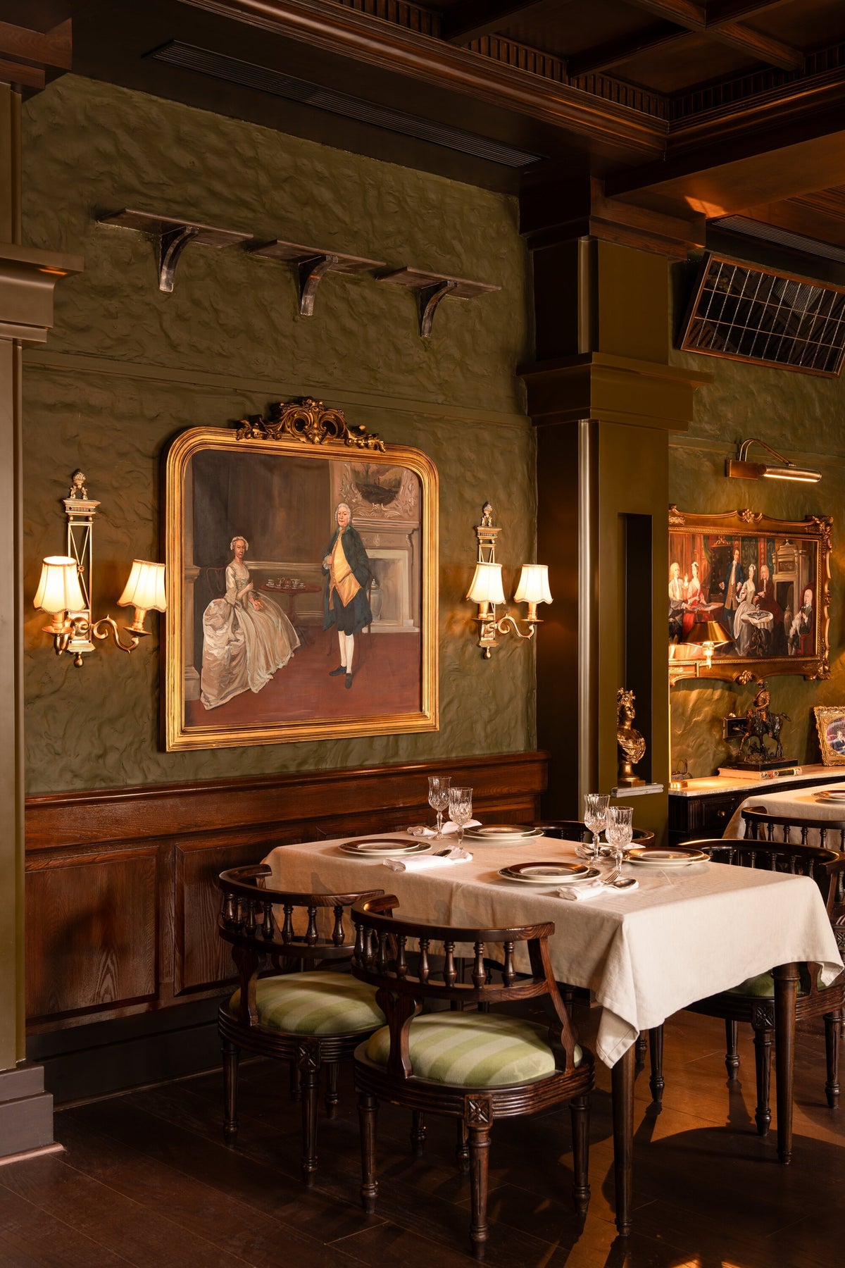 Pair of Directoire brass wall lights flanking a gilt-framed portrait on a green wall at The Governor House, Amritsar – Renesa Architecture Studio, photo Avesh Gaur