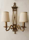 Directoire Brass Double Wall Light, antique brass X-frame backplate with urn finial, two scroll arms and ivory linen shades, front view