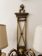 Close-up of the antique brass flame urn, dentilled cornice and X-cross backplate with rosette