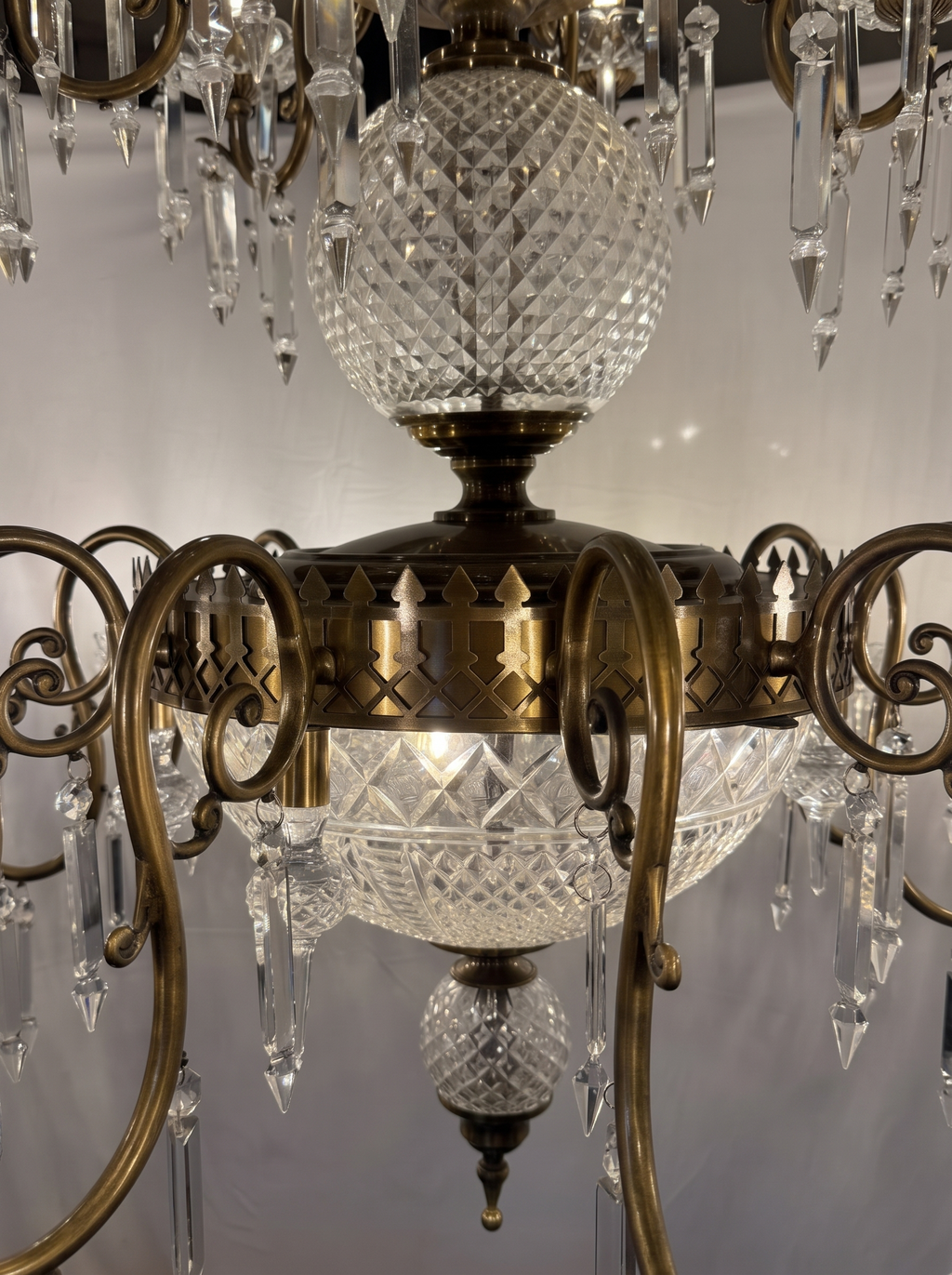 Close-up of the diamond-cut crystal globe, pierced brass gallery, cut-glass bowl and brass scroll arms