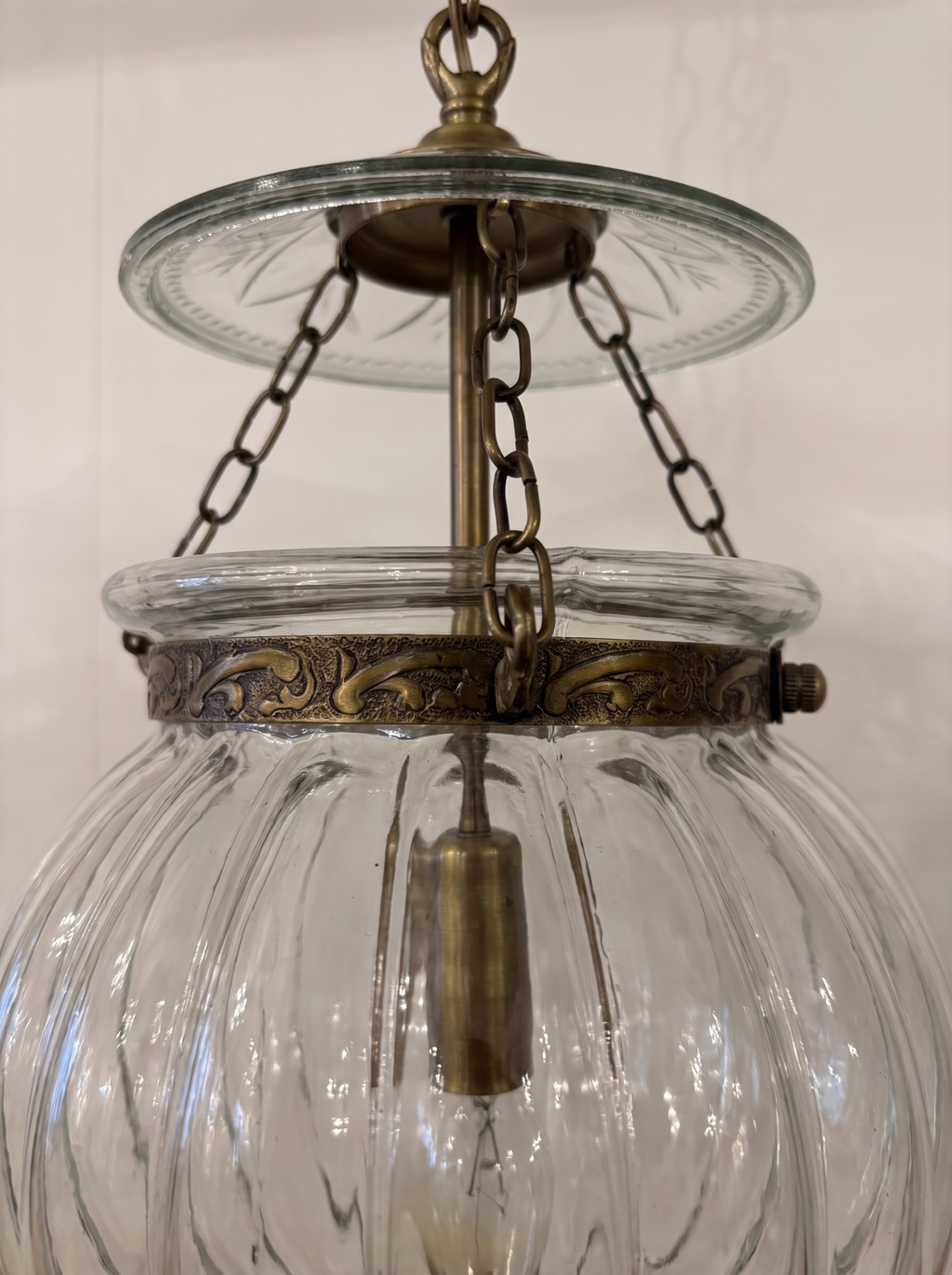 Close-up of the cut-glass smoke plate, brass chains and hand-embossed repoussé brass band on the ribbed glass globe