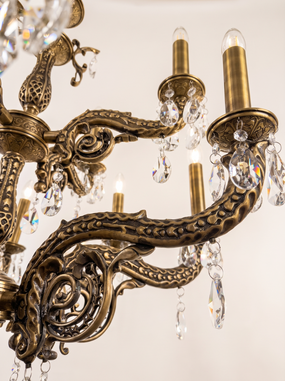 Close-up of a pierced cast brass Granada arm, crystal pendeloques and a tall brass candle sleeve
