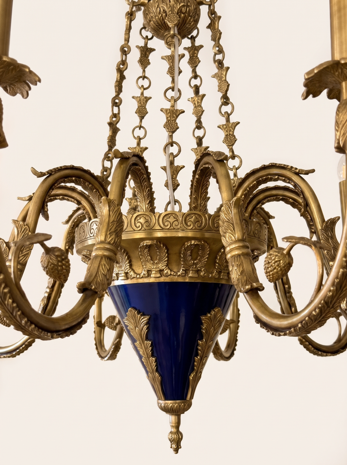 Close-up of the cobalt-blue body with cast brass acanthus mounts, anthemion gallery, leaf chains and pinecone-hung arms
