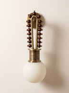 Mala Wall Light in antique brass with polished wood beads and a frosted glass globe, front view