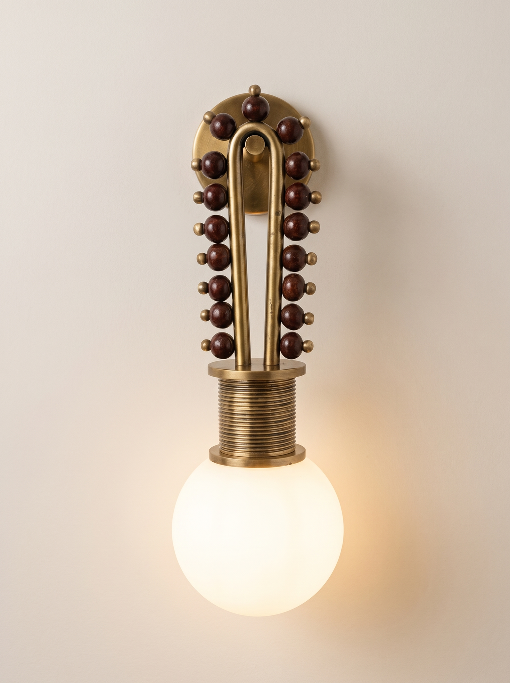 Mala Wall Light switched on, the frosted glass globe glowing warm