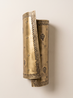 Patra Scroll Sconce in antique brass, front view, mounted on a plain wall