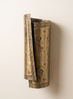 Patra Scroll Sconce three-quarter view, showing the rolled brass sheet and its hammered border