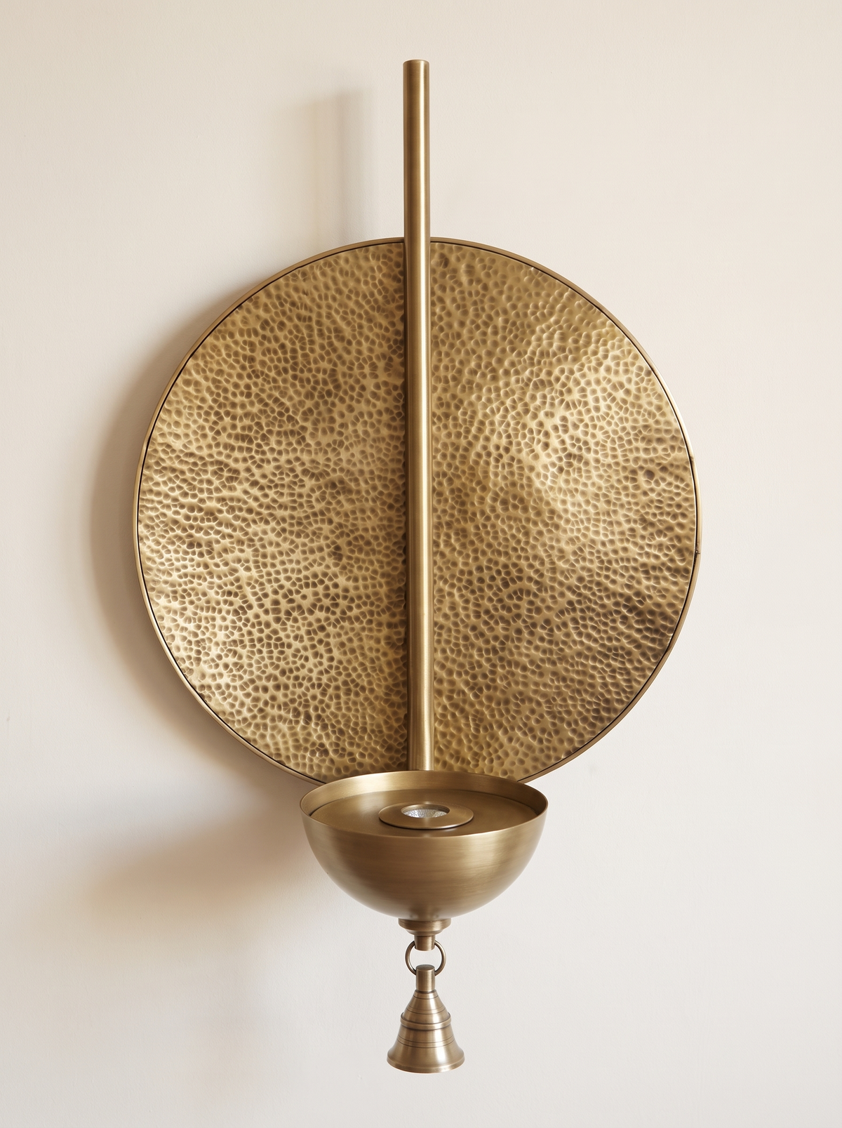 Prabha Halo Wall Light, hand-beaten brass disc with rod, bowl and temple bell, front view