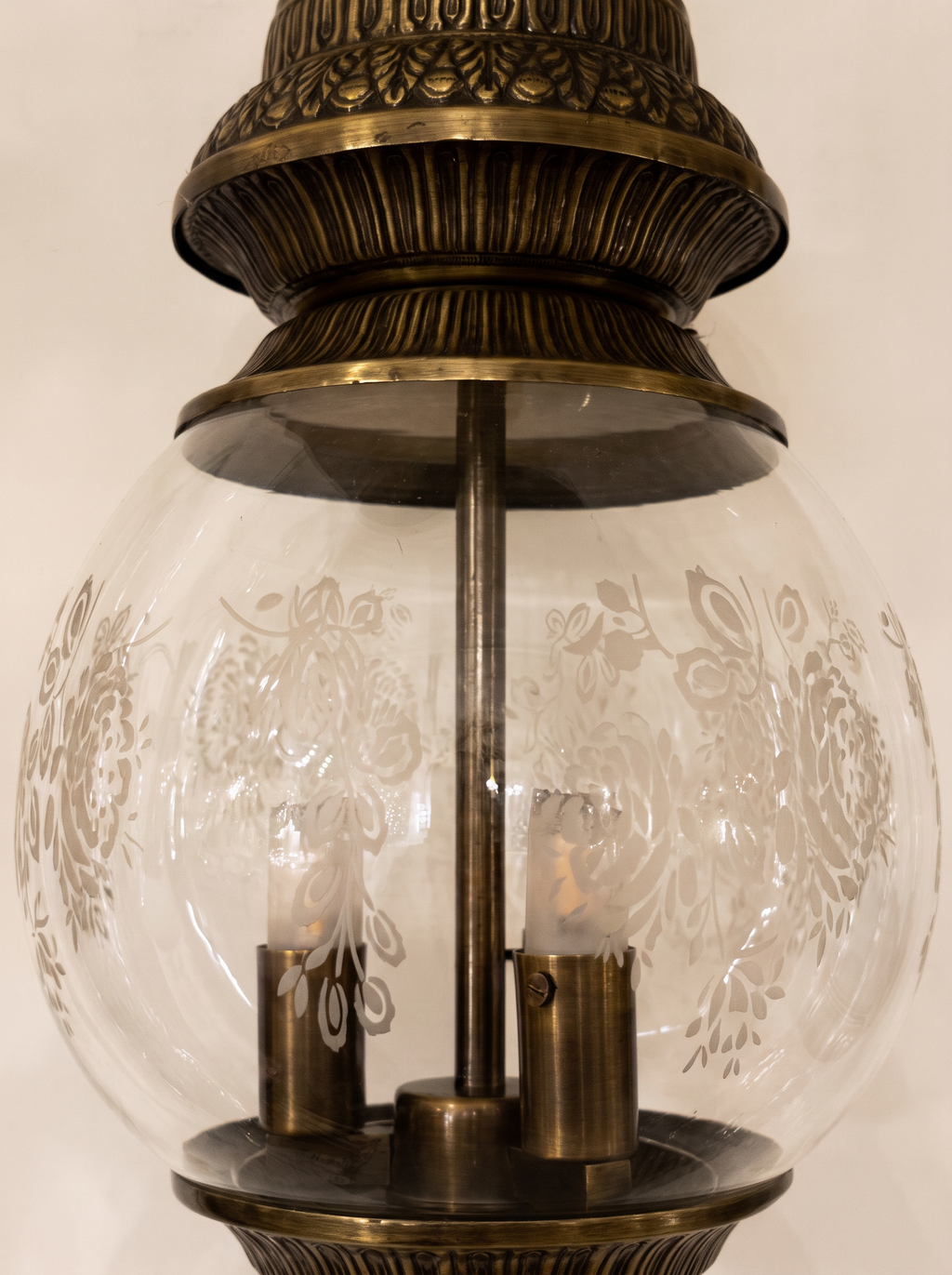 Close-up of the frosted rose motifs on the clear glass globe and the ribbed brass crown