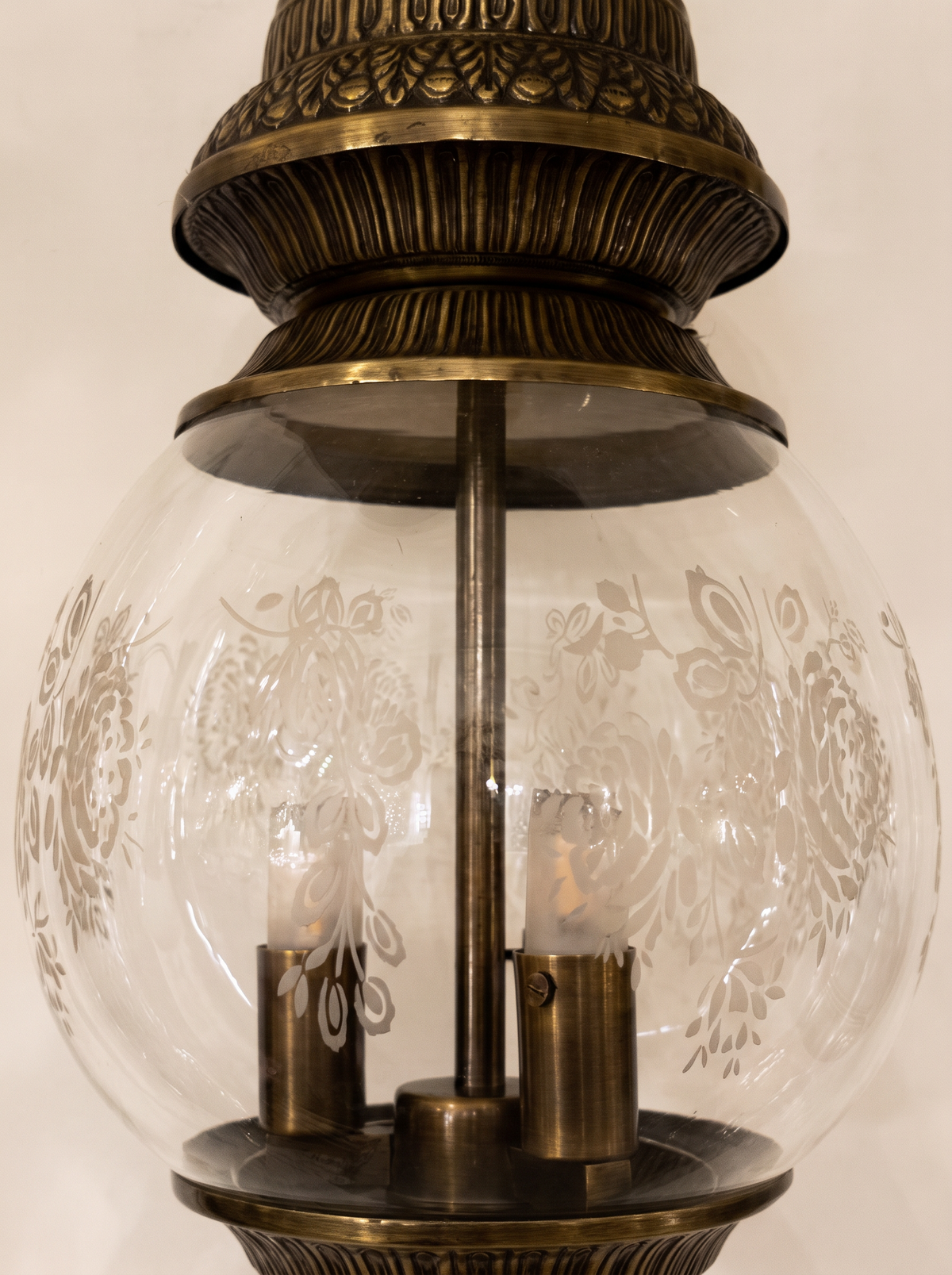 Close-up of the frosted rose motifs on the clear glass globe and the ribbed brass crown