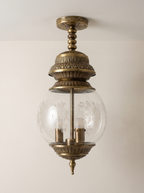 Qandeel Pendant Light in antique brass with an embossed crown and a clear glass globe banded with frosted roses, front view