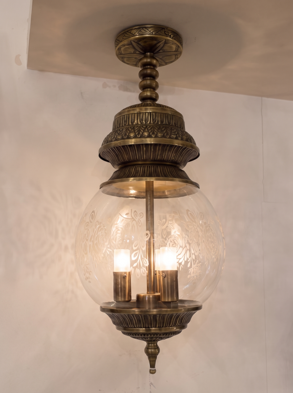 Qandeel Pendant Light switched on, three bulbs glowing inside the etched glass globe