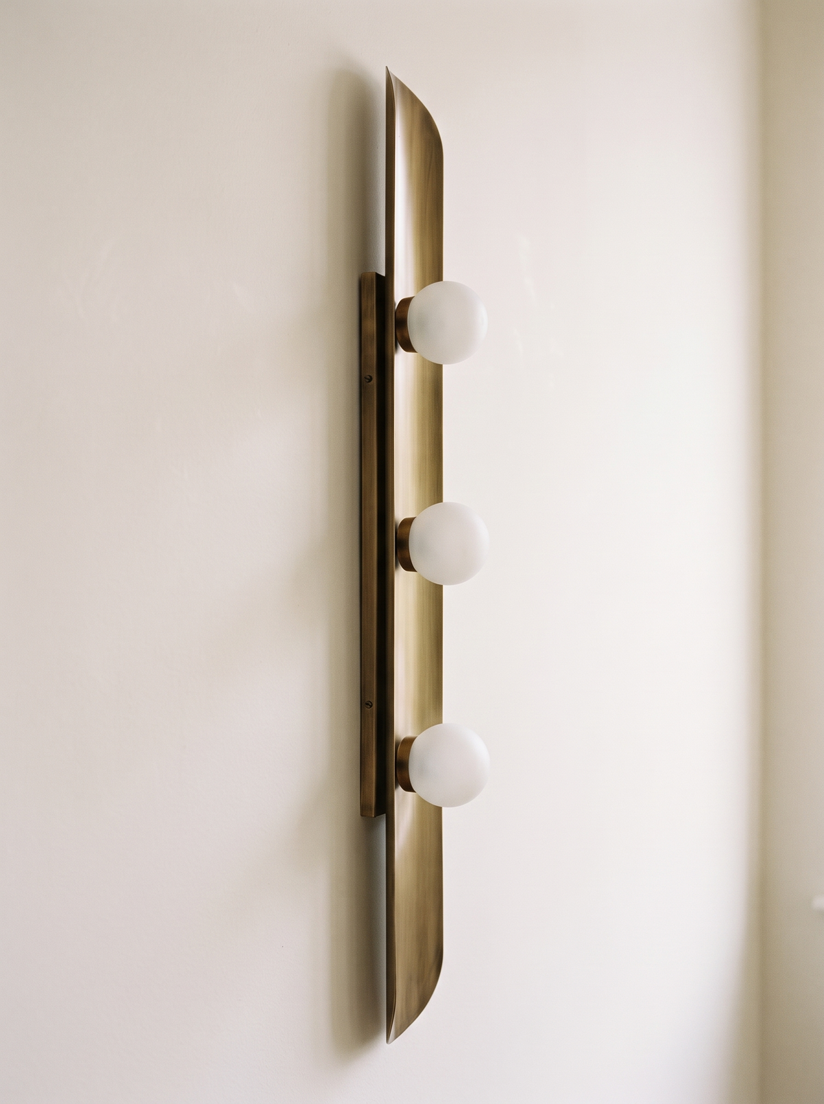Reed Wall Light side view, showing the shallow curve of the brass sheet, the slanted end and the slim backbar