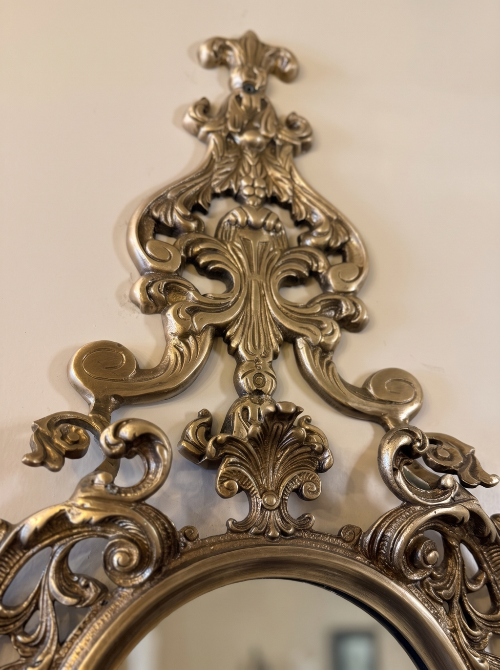 Close-up of the cast brass crest of C-scrolls, acanthus leaves and fleur-de-lis above the mirror