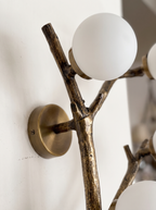 Close-up of the cast brass bark texture, knots and twig stubs, with opal globes in brass cups