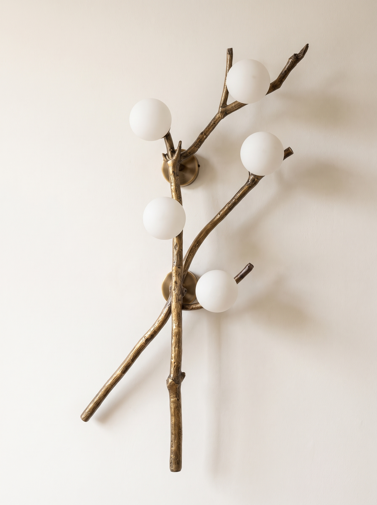 Shakha Branch Wall Light in antique cast brass with five opal glass globes, front view on a plain wall