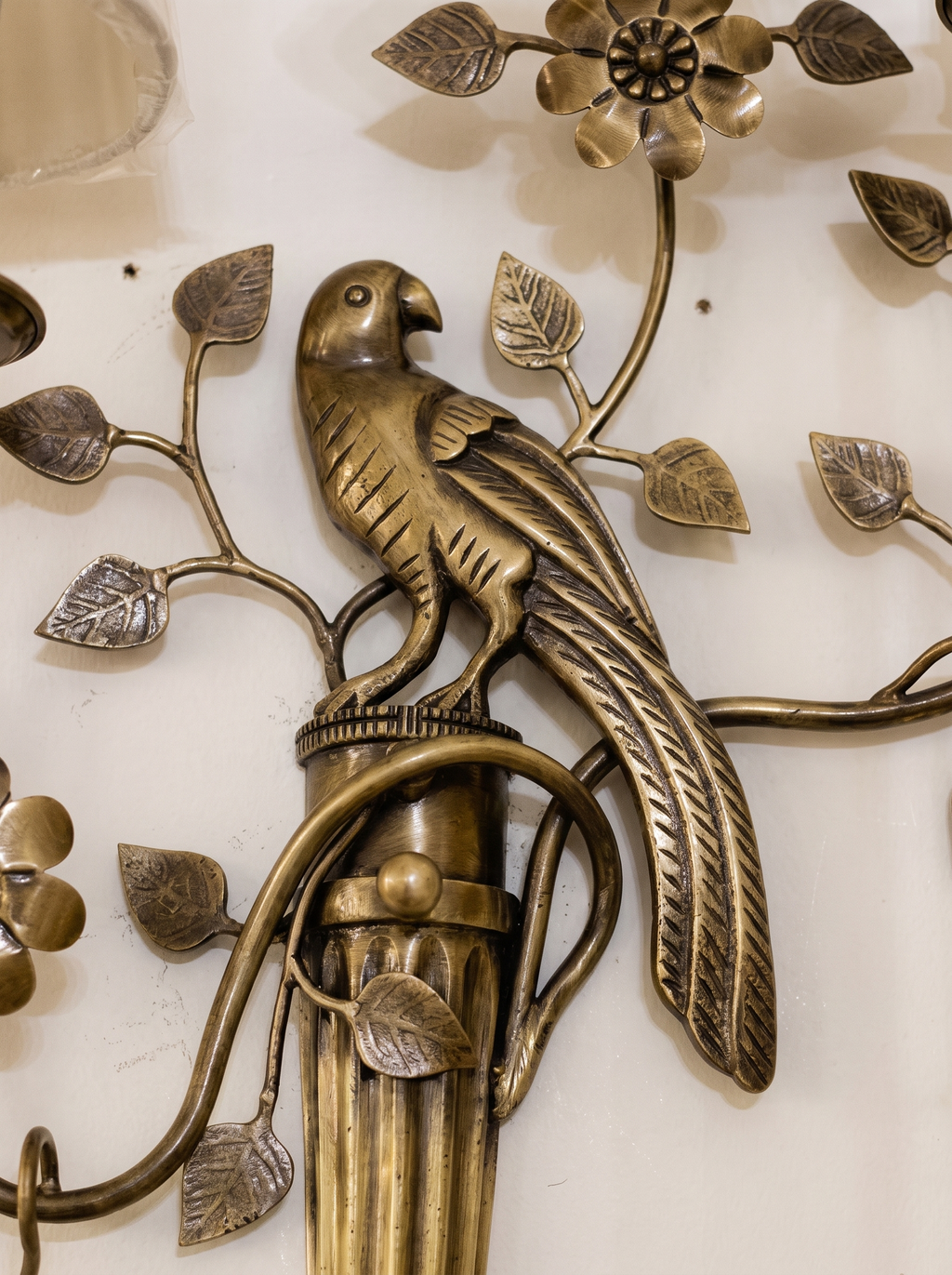 Close-up of the cast brass parrot perched on the fluted column, with veined leaves and a flower