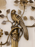 Close-up of the cast brass parrot perched on the fluted column, with veined leaves and a flower