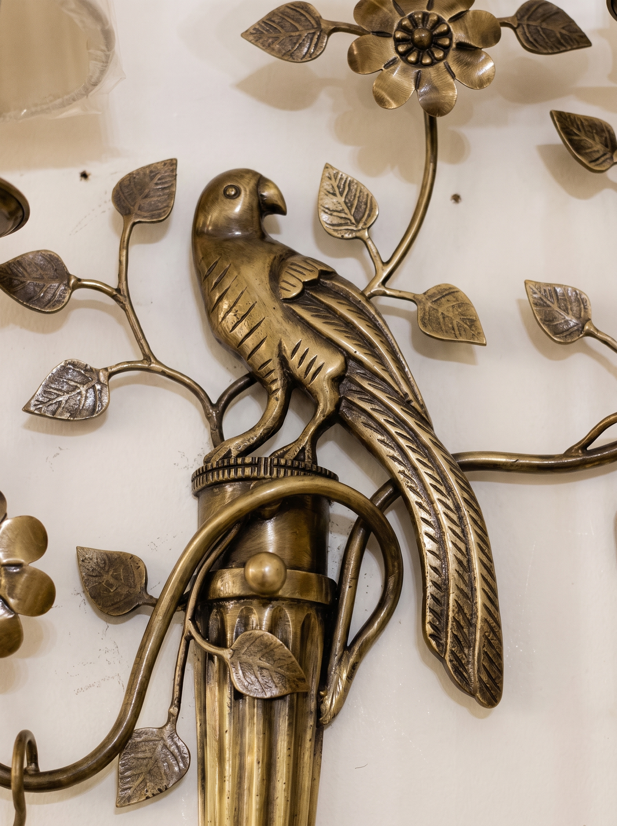 Close-up of the cast brass parrot perched on the fluted column, with veined leaves and a flower