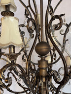 Close-up of the black and gold scrolls, crystal drops, central ball and urn column, and ivory shades with gold braid trims